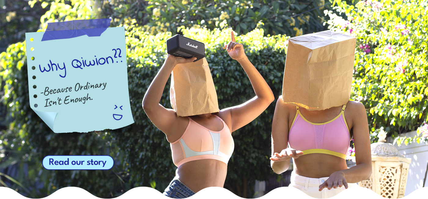 Two people with paper bags over their heads, one holding a sign with text, against a green outdoor background.
