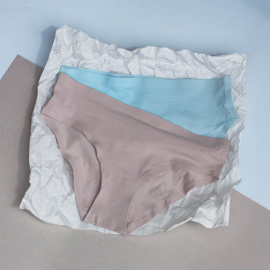 Two pairs of underwear, one light grey and one blue, on a textured surface with a light blue background.