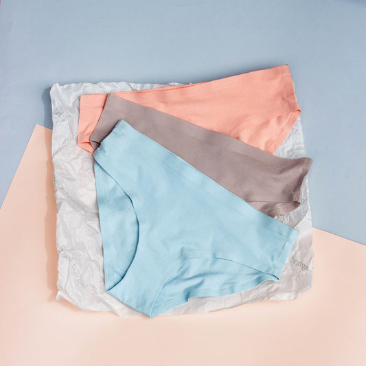 Three pairs of underwear in blue, gray, and pink on a light blue background