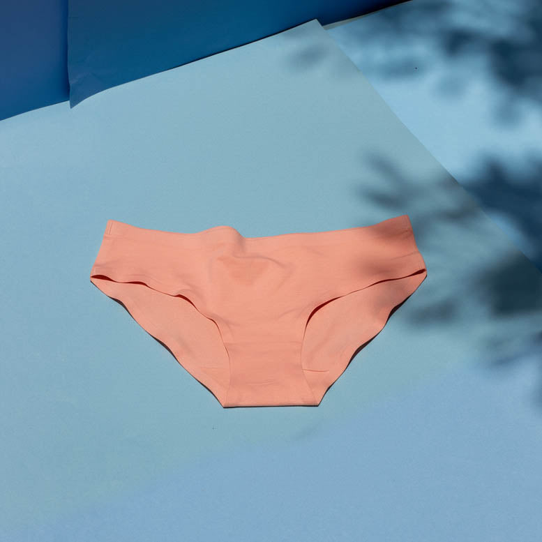 Peach-colored underwear on a blue surface