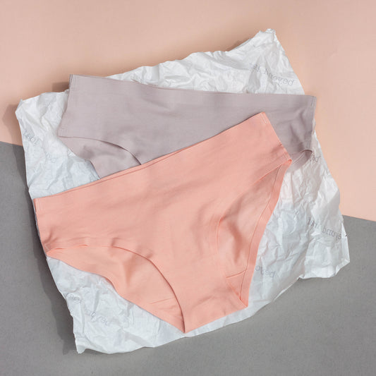 Pair of underwear in peach and grey, on a neutral background