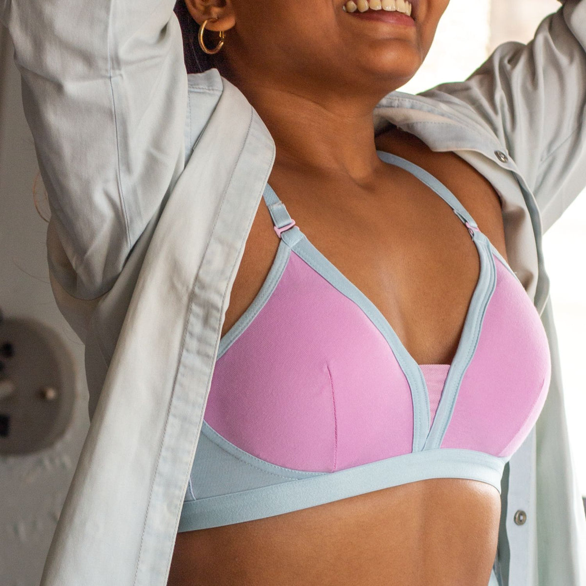 A woman wearing a Qiwion bra in pink and blue with a light grey jacket.