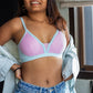 Woman wearing a light blue and pink bralette with a blurred background
