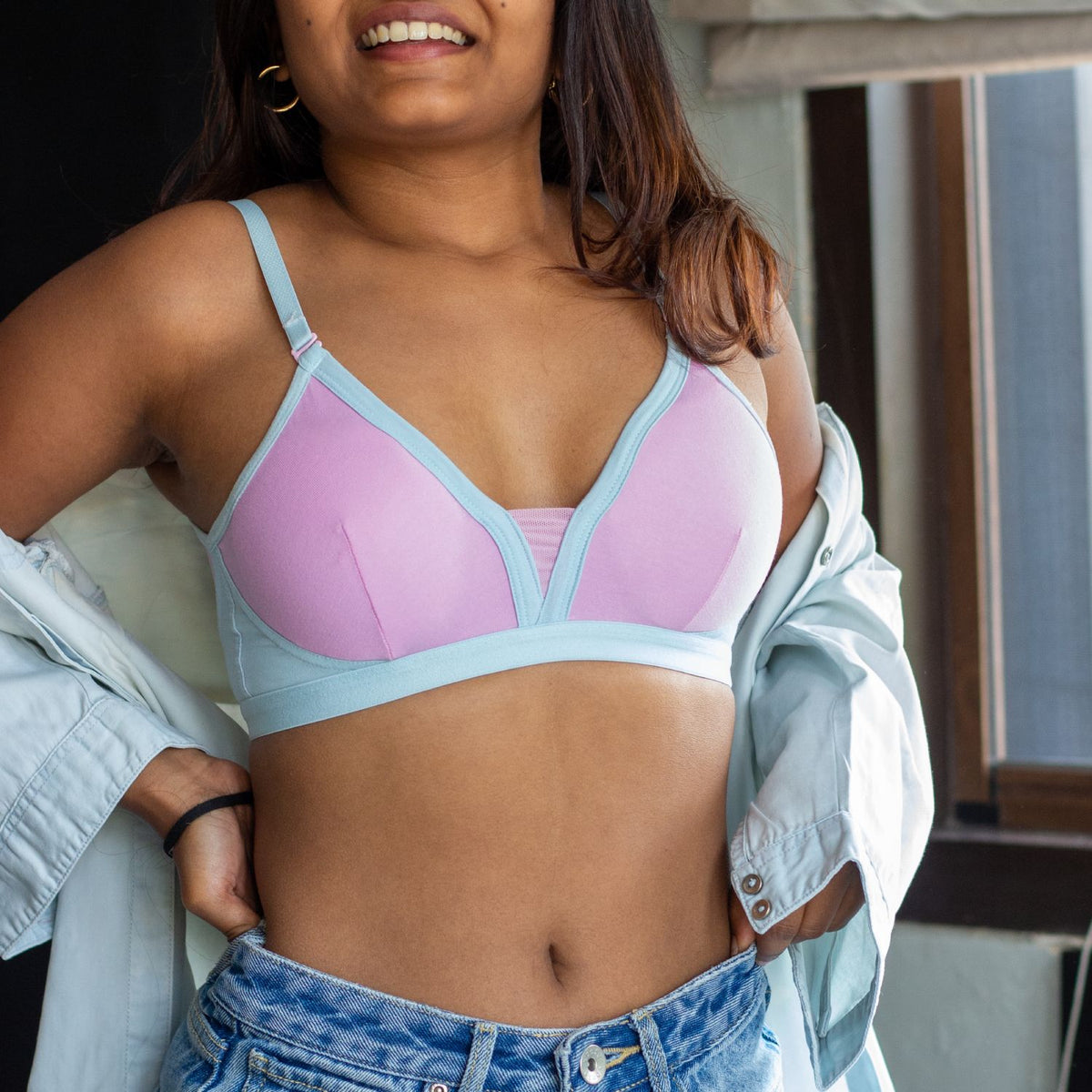 Woman wearing a light blue and pink bralette with a blurred background