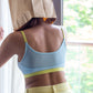 Person wearing Qiwion mood bra in a light blue colour, with neon straps and underband and mesh back