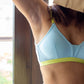 Light blue sports bra with green band worn by a person. Padded bra design. 