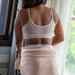 Person wearing a beige bra and holding a towel in a room with a window in the background