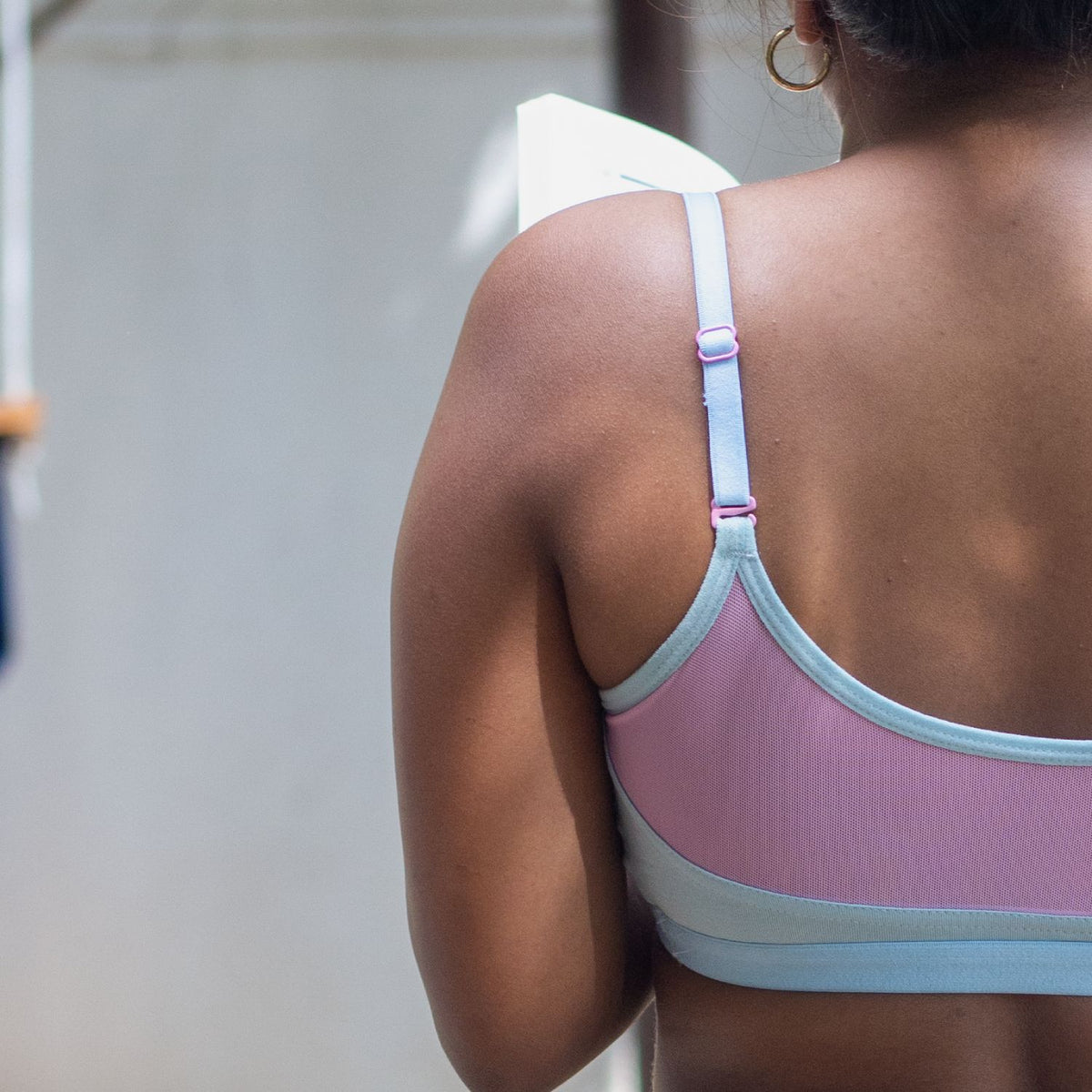 Person wearing a pink and light blue Qiwion bra, with adjustable straps -  with a blurred background