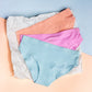 Three pairs of blue, pink, peach underwear on a textured surface with a light blue background