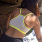 Person wearing a qiwion jumpstart bra in light grey, with neon straps in an outdoor setting