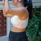 Person wearing a light pink and cream bra and shorts outdoors with plants in the background. side profile also shows mesh details on the bra
