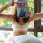 girl holding a book, wearing qiwion one and done bra in a light cream and pink shade